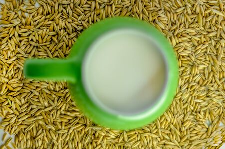 green mug with milk. healthy eating. good food. delicious drink. oat milk. Suitable for writing articles about diet, oat products, recipes. white background, scattered oat seeds.の写真素材