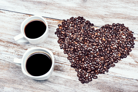 two cups of coffee with beans in the shape of the heartの写真素材