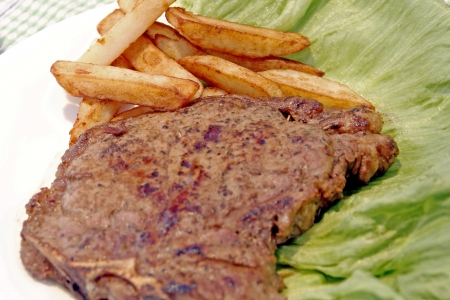 A beef steak garnish with french fries and lettuceの写真素材