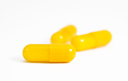 Three yellow vitamin C capsules with white background の写真素材