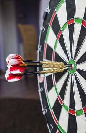 A dartboard close-up with three bullseye hits.