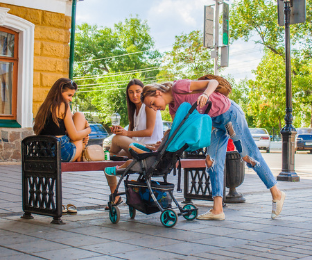 Orenburgburg, Russia - August 16, 2017: a meeting of young pretty women at the bench in the street with the child's participation in the carriage.のeditorial素材