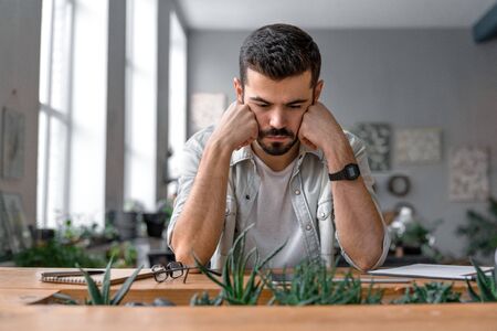 Close up shot of caucasian office worker Pensive manager sitting beside his desktop and reading...