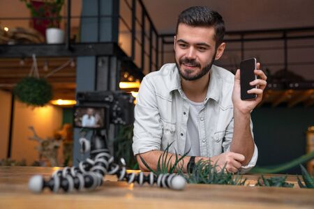 Young male blogger recording camera tripod