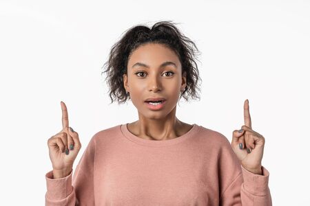 Close up portrait of woman pointing fingers at copy space isolated over white background
