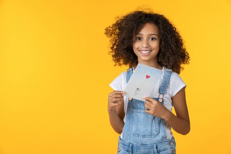 Portrait of beautiful girl holding greeting card isolated on yellow background