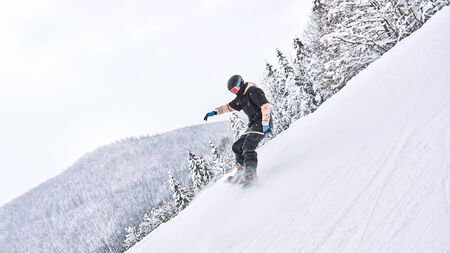 Making some moves. Male snowboarder is riding from the snowy hill while making some extreme moves