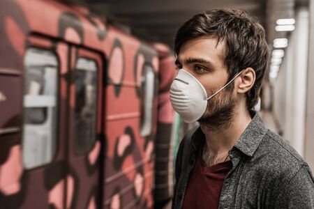 Young man in protection mask against virus at public train station