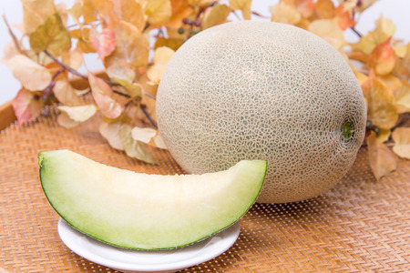 Fresh ripe organic cantaloupe melons in a basket on maple leaves backgroundの写真素材