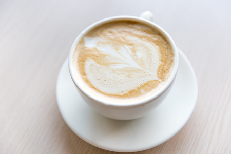 Hot art Latte Coffee in a cup on wooden tableの写真素材