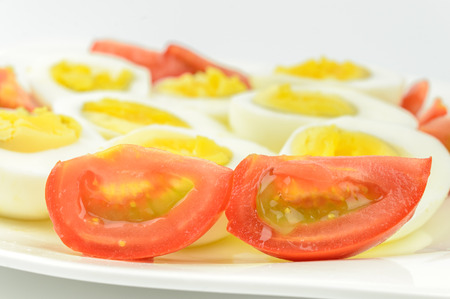tomatoes and boiled eggs on a white plateの写真素材