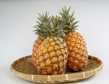 pineapple on a bamboo basket isolated on white backgroundの写真素材