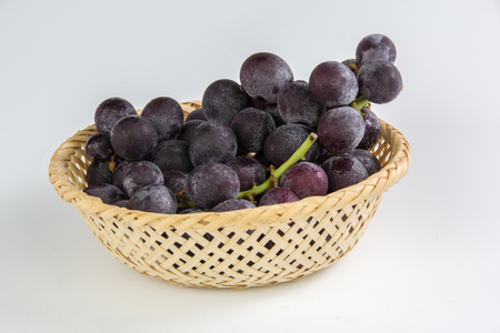 Grapes in bamboo basket isolated on white backgroundの写真素材