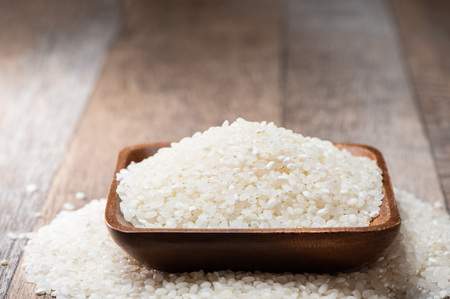 Raw rice in a wooden bowl on wooden backgroundの写真素材