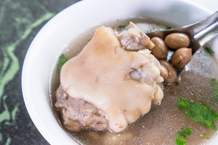 Taiwan's distinctive famous snacks: Peanut pork knuckle(pig's trotter) soup in a white bowl on stone table, Taiwan Delicacies, Taiwan Street Foodの写真素材