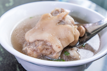 Taiwan's distinctive famous snacks: Peanut pork knuckle(pig's trotter) soup in a white bowl on stone table, Taiwan Delicacies, Taiwan Street Foodの写真素材