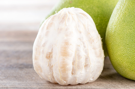 fresh and peeled pomelo(shaddock), grapefruit with slices on wooden table backgroundの写真素材