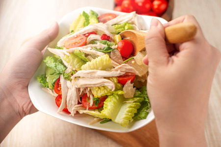 Fresh and delicious homemade chicken salad with tomatoes and pomelos in wooden background, concept of healthy and diet, top view, copy spaceの写真素材