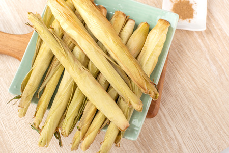 Delicious homemade izakaya-like roast baby corn in wooden background, Taiwan delicacies, top view,...