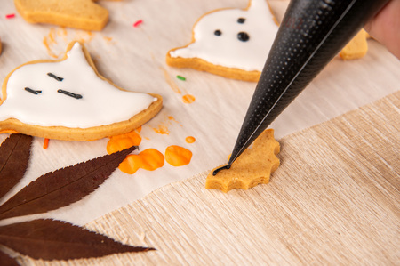 Fresh homemade decorating halloween cookies with ghost, creeping spider, bat, haunted castle and horrifying eyeball on wooden background, copy spaceの写真素材