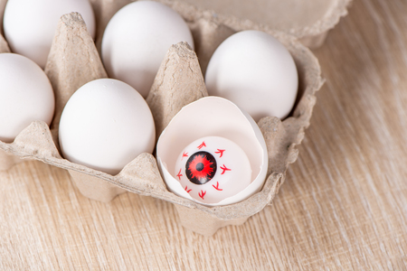 Funny halloween treats, eyeball in egg on wooden background, copy space, closeupの写真素材