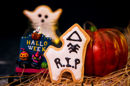 Fresh homemade decorated halloween cookies and sweets on dark background, concept of halloween monster party, copy space, close upの写真素材