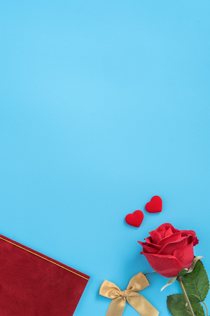 Red greeting card with golden bow at Valentine's day, anniversary, mother's day and birthday for a surprise on blue background, copy space, top viewの写真素材