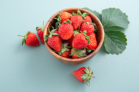 A bowl of beautiful and delicious strawberries isolated on a blue-green background, closeup, topview, copyspace.の写真素材