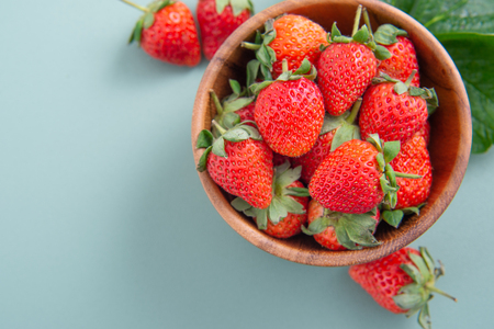 A bowl of beautiful and delicious strawberries isolated on a blue-green background, closeup, topview, copyspace.の写真素材