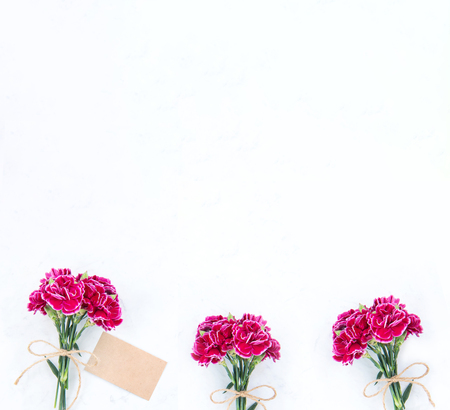 May mothers day idea concept photography - Beautiful blooming carnations tied by bow with kraft text card isolated on bright modern table, copy space, flat lay, top view, mock upの写真素材
