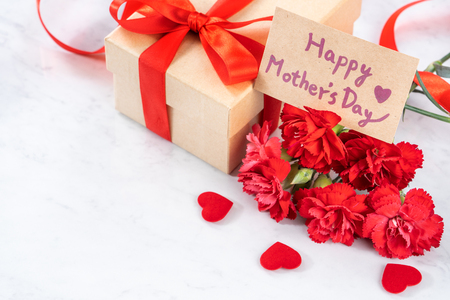 May mothers day handmade giftbox wishes photography - Beautiful blooming carnations with red ribbon bow box isolated on modern marble desk, close up, copy space, mock upの写真素材
