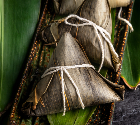 Close up, copy space, top view, famous asian chinese tasty handmade food in dragon boat(duan wu) festival, steamed rice dumplings shaped pyramidal by leaves ingredientsの写真素材