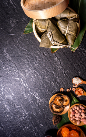Close up, copy space, top view, flat lay. Famous asian chinese tasty handmade food in duan wu event, steamed rice dumplings shaped like pyramidal ingredient on black slateの写真素材