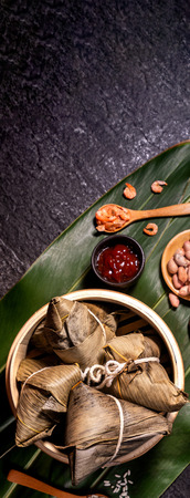 Close up, copy space, top view, flat lay. Famous asian chinese tasty handmade food in duan wu event, steamed rice dumplings shaped like pyramidal ingredient on black slateの写真素材