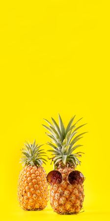 Creative pineapple   with sunglasses isolated on yellow background, summer vacation beach idea design patternの写真素材