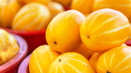Delicious korean stripe yellow melon fruit food in red plastic basket at tradition market afternoon, Seoul, South Korea, harvest concept, close up.の写真素材