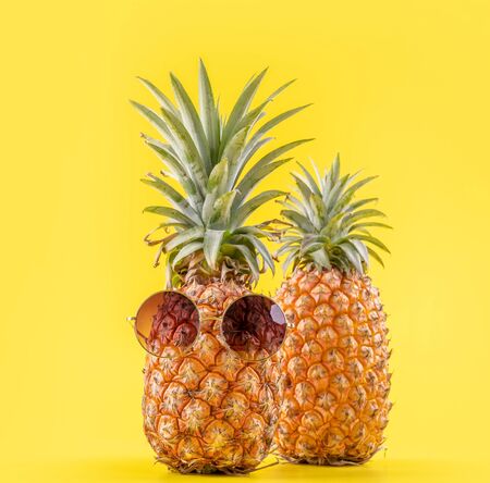Creative pineapple with sunglasses isolated on yellow backgroundの写真素材