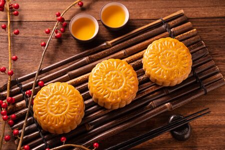 Moon cake Mooncake table setting - Round shaped Chinese traditional pastry with tea cups on wooden background, Mid-Autumn Festival concept, close up.の写真素材