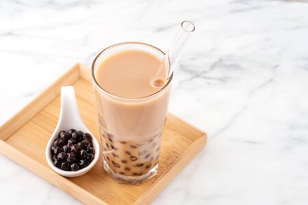 Taiwanese popular beverage - Pearl milk tea on wooden dish over marble white tableの写真素材
