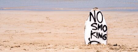 No Smoking warning sign on white surfboard at the beach in summer, concept of sea environmantal protection design, copy space, lifestyle.の写真素材