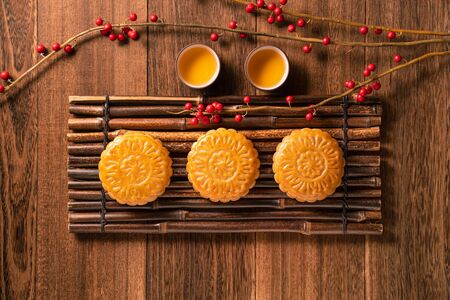 Chinese traditional pastry Moon cake Mooncake with tea cups on bamboo serving tray on wooden background for Mid-Autumn Festival, top view, flat lay.の写真素材