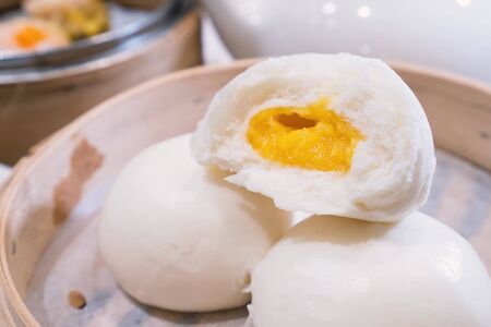 Delicious dim sum, famous cantonese food in asia, fresh and hot salted creamy custard buns in bamboo steamer in hong kong yumcha restaurant, close up