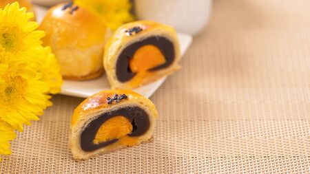 Tasty baked egg yolk pastry moon cake for Mid-Autumn Festival on bright wooden table background. Chinese festive food concept, close up, copy space.の写真素材