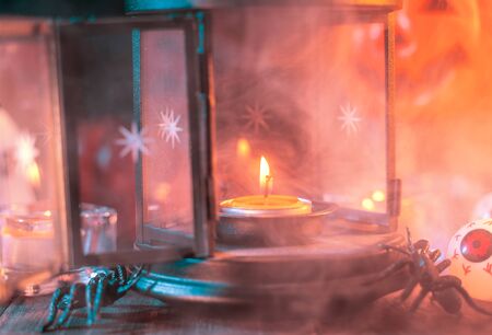 Halloween concept, spooky decorations with lighting up candle with smoke around on a dark wooden table, close up.の写真素材