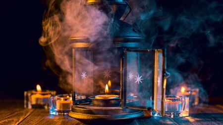 Halloween concept, spooky decorations with lighting up candle with green smoke around on a dark wooden table, close up.の写真素材