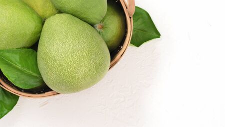Fresh pomelos grapefruit in bamboo basket with green leaf on white background. Seasonal fruit for Mid-Autumn Festival. Top view. Flat lay.の写真素材
