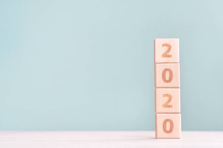 New Year 2020 design concept - wood blocks on wooden table and gray green background, close up, copy space.の写真素材