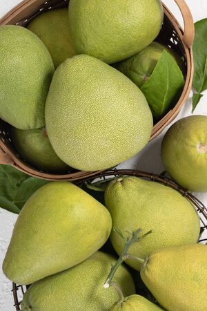 Fresh pomelo, pummelo, grapefruit, shaddock on white cement background in bamboo basket. Autumn...
