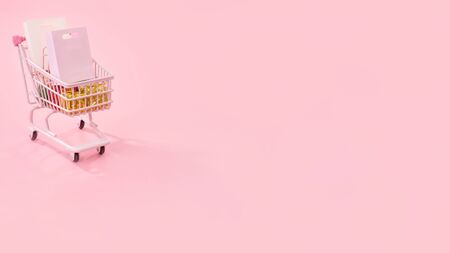 Annual sale shopping season concept - mini pink shop cart trolley full of paper bag gift isolated on pale pink background, blank copy space, close upの写真素材