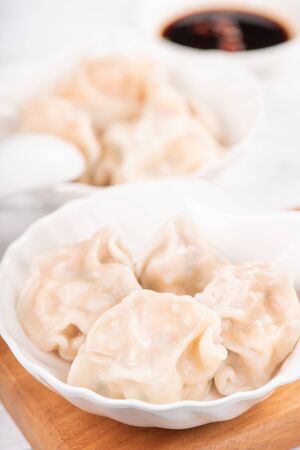 Fresh, delicious boiled pork, shrimp gyoza dumplings on white background with soy sauce and chopsticks, close up, lifestyle. Homemade design concept.の写真素材